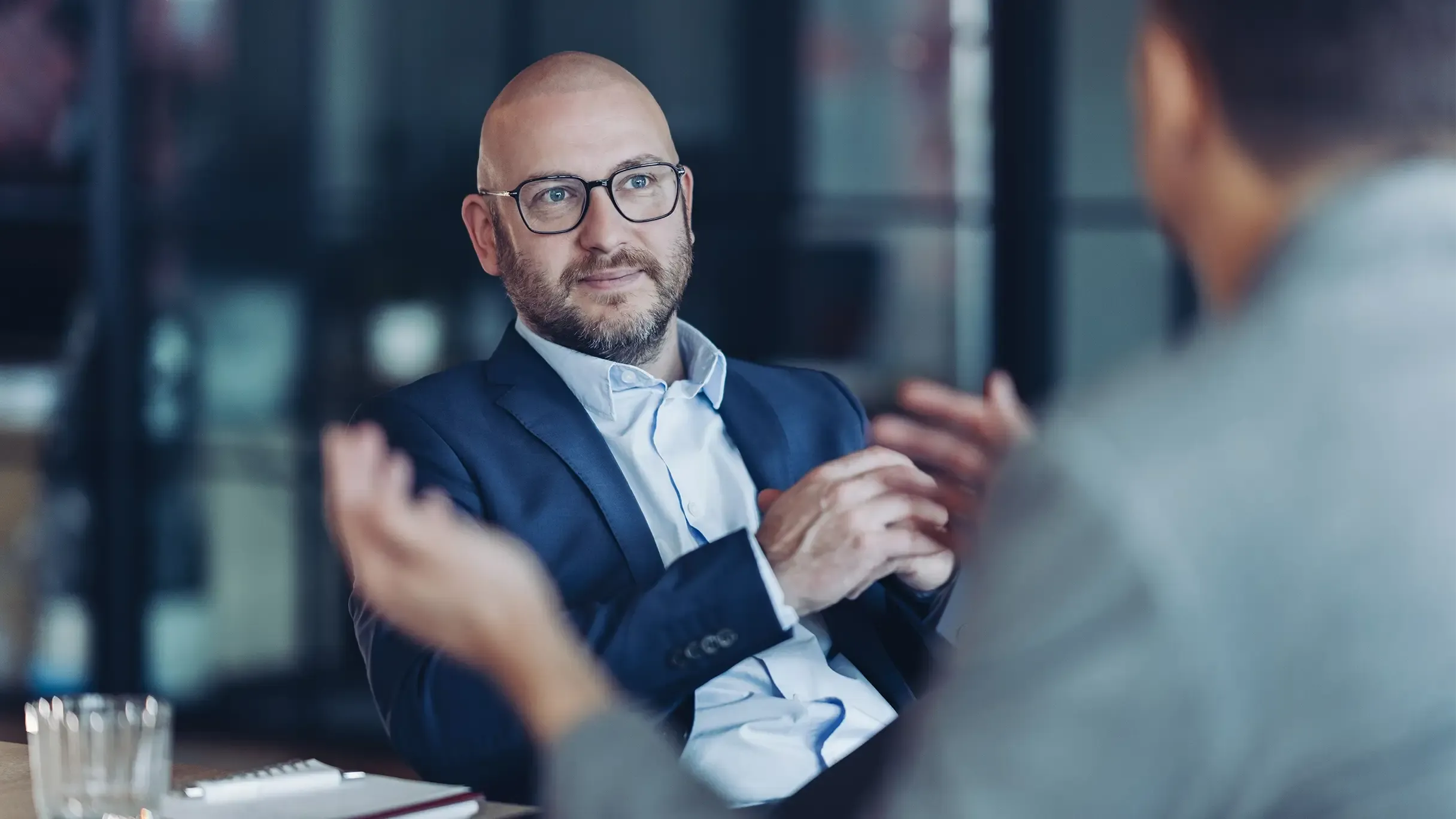A bearded businessman wearing black, rectangular eyeglasses.