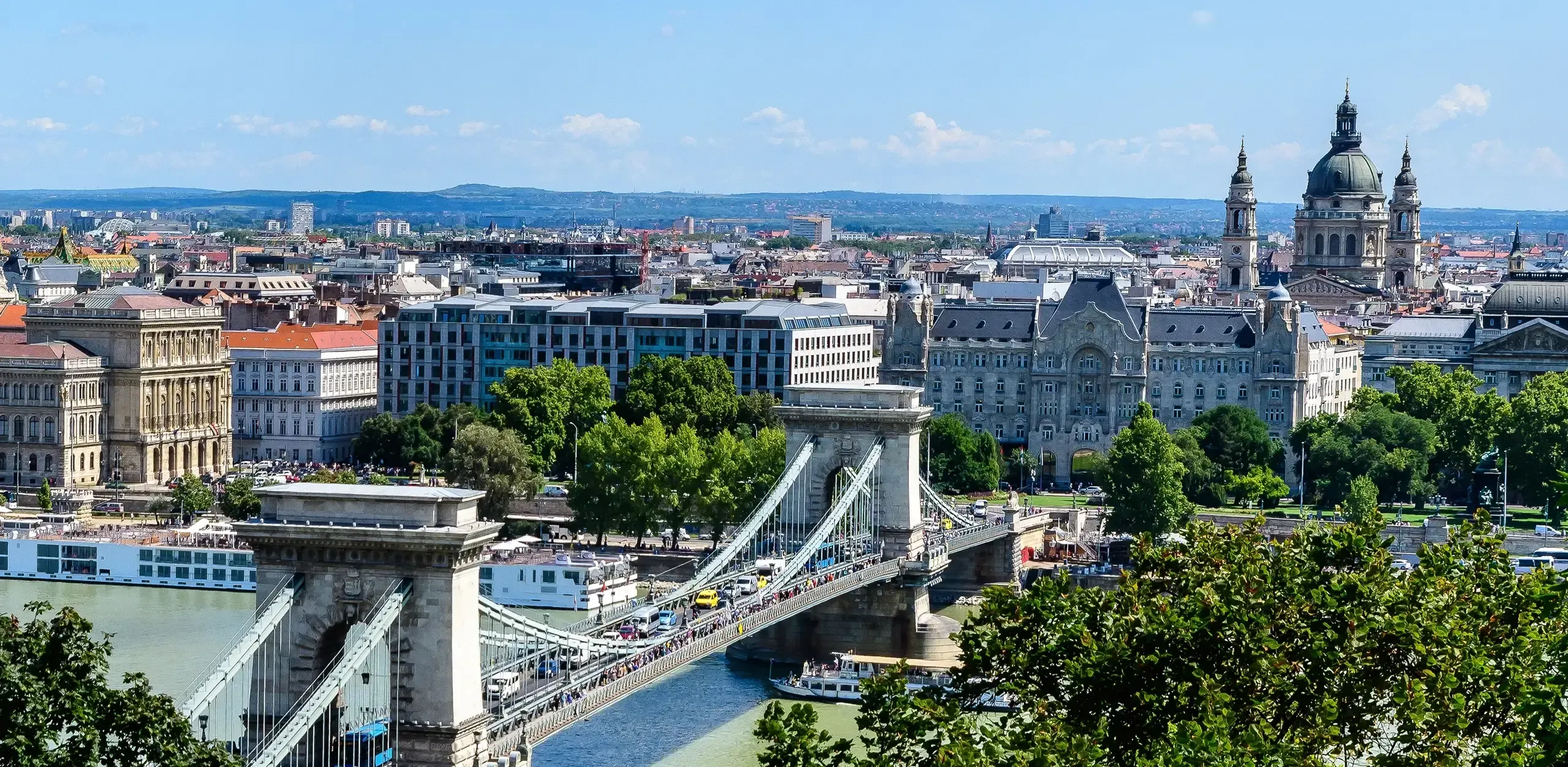 Széchenyi Chain Bridge crossing the Danube River in Budapest under a clear blue sky.